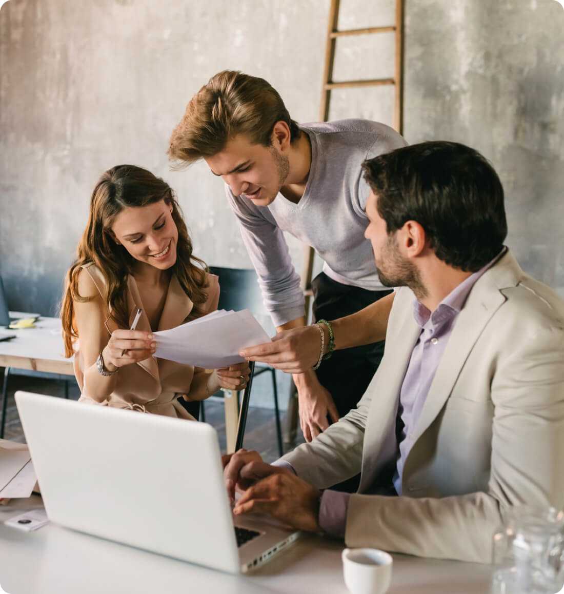 Tre professionisti lavorano insieme al laptop per creare il sito per la loro attività. 