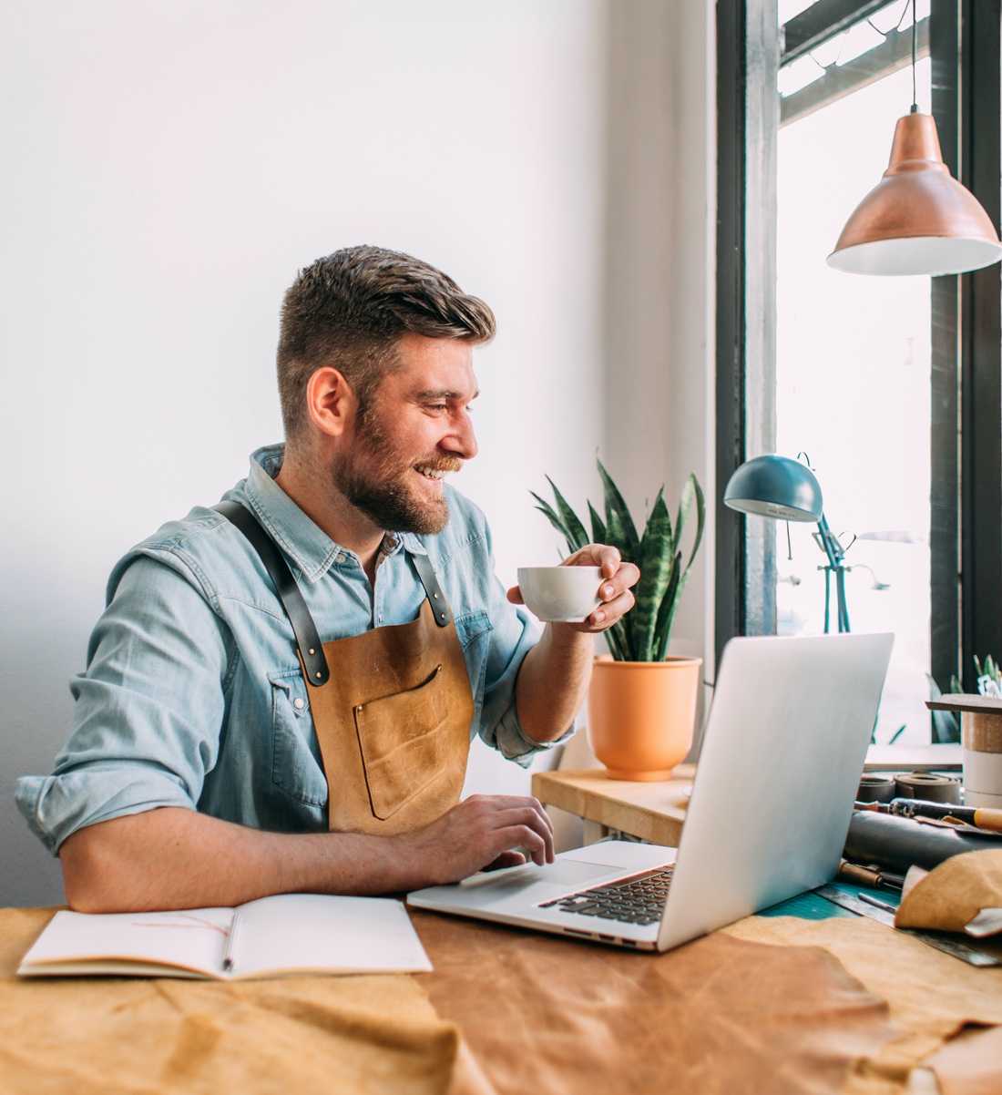 Een leerbewerker zit aan zijn bureau en bewerkt zijn Jimdo-website.