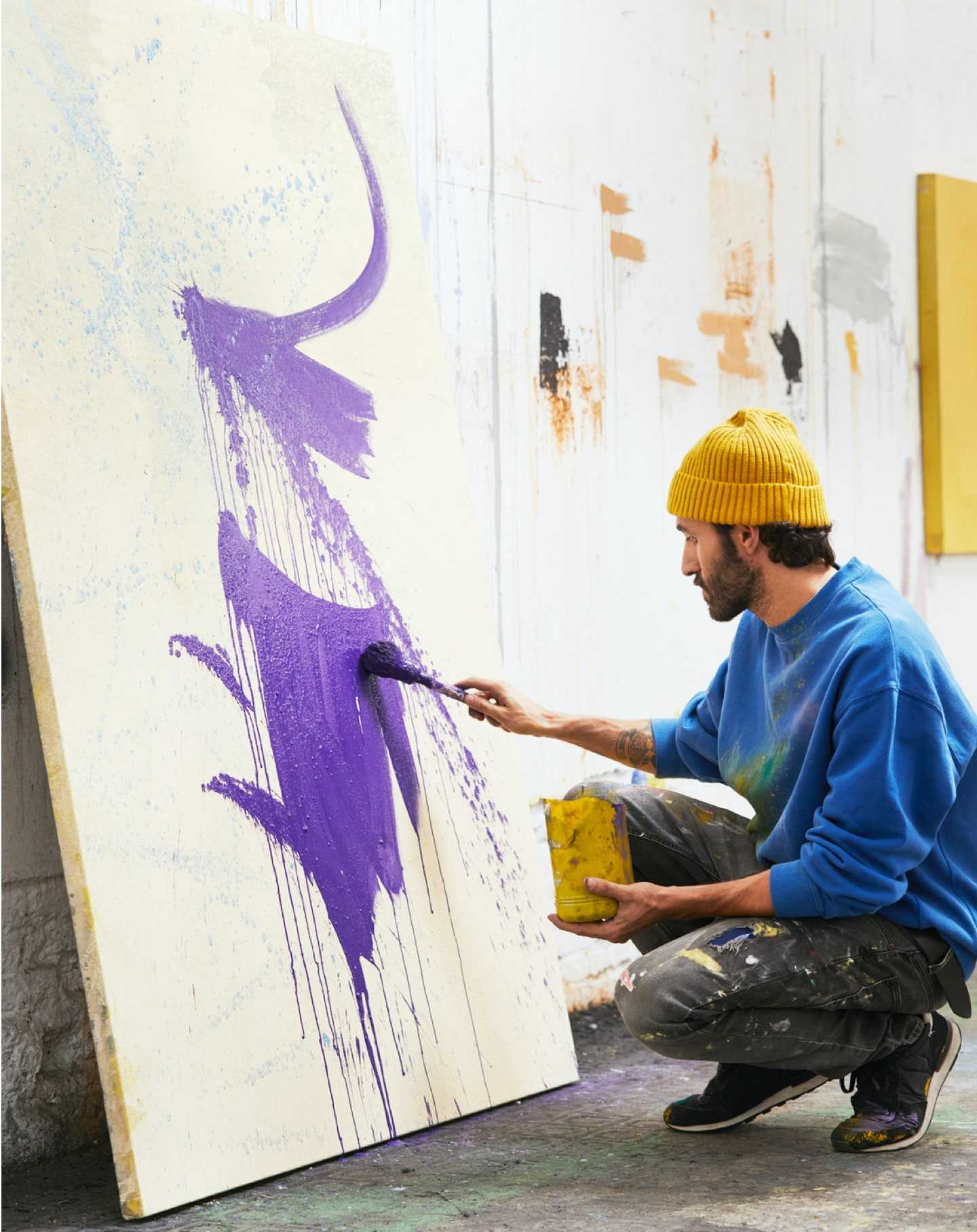 An artist in her studio works on a painting for her painter website